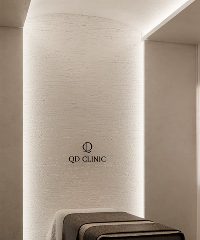 Ein Behandlungsraum der QD Clinic, das Klinikzeichen an der Wand